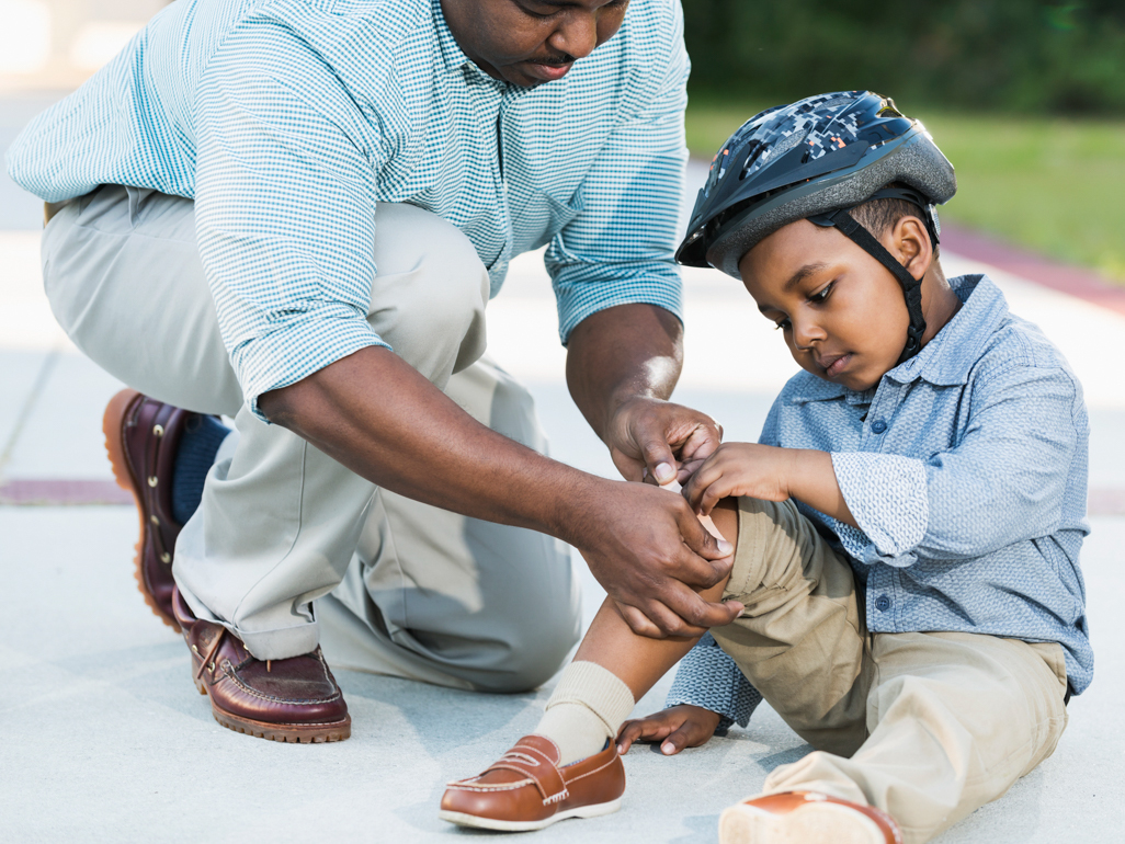 dad putting bandage on sons knee injury