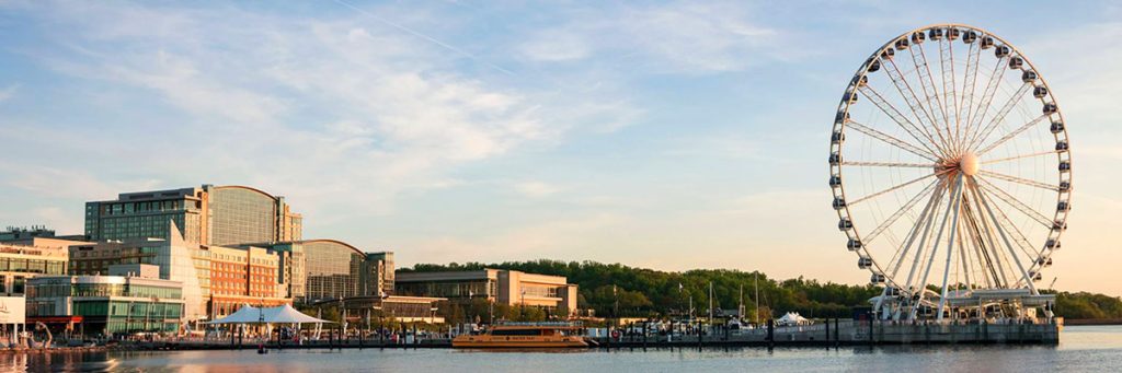 Gaylord National Resort and Convention Center (on left) with a ferris wheel (on right) reflecting in the Potomac River at sunrise.