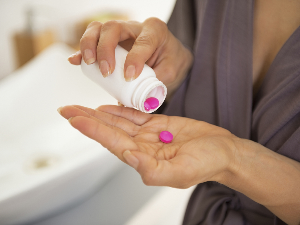 woman taking a pink allergy pill