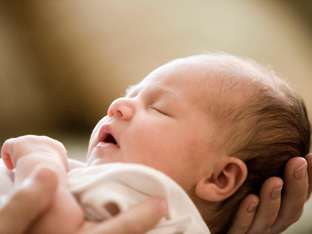 Newborn sleeping in his parent's arms