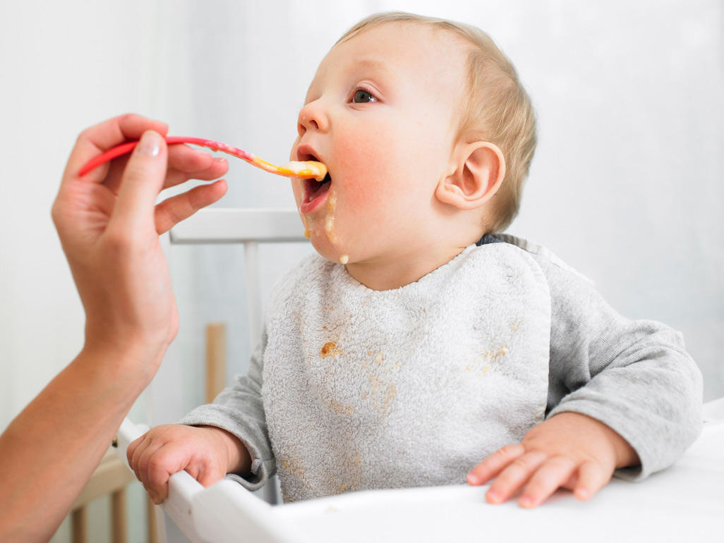 Baby being spoon-fed puree