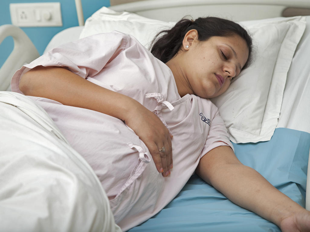 Pregnant woman lying on side in hospital bed