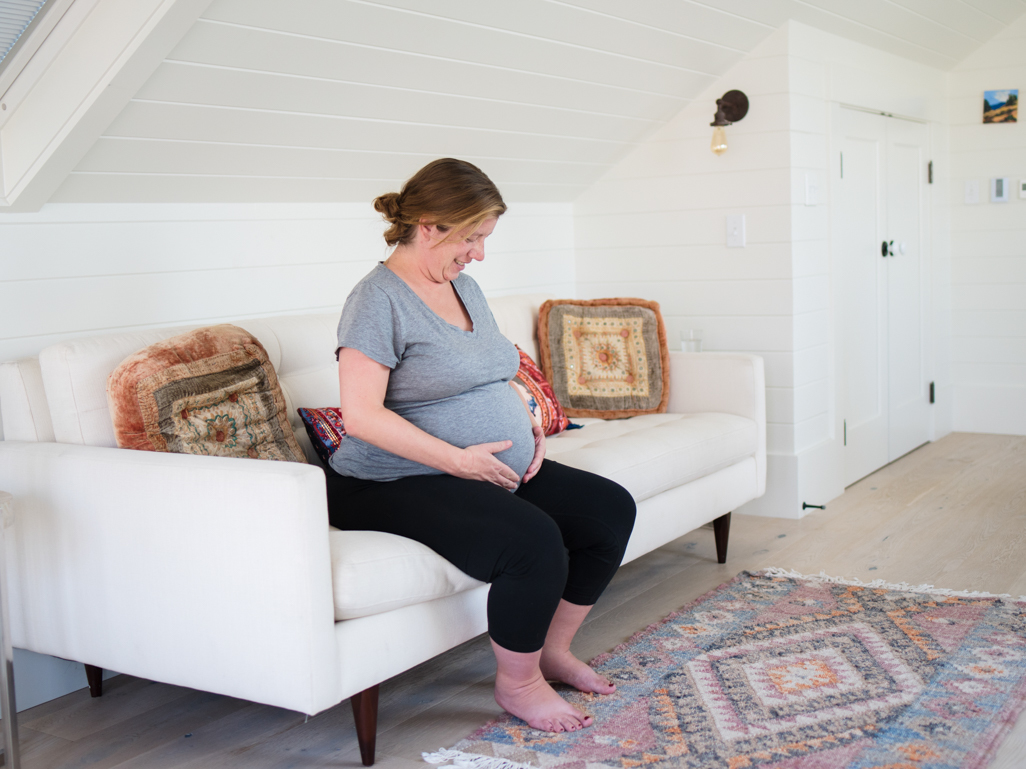 Pregnant woman sitting on a sofa with her hands on her bump