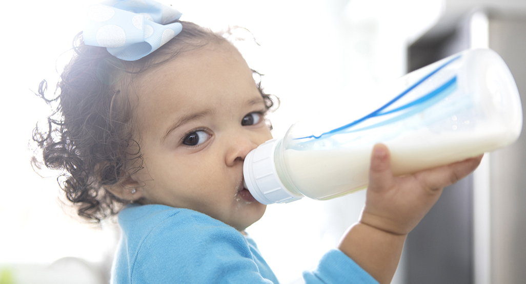 girl holding a baby bottle and drinking from it