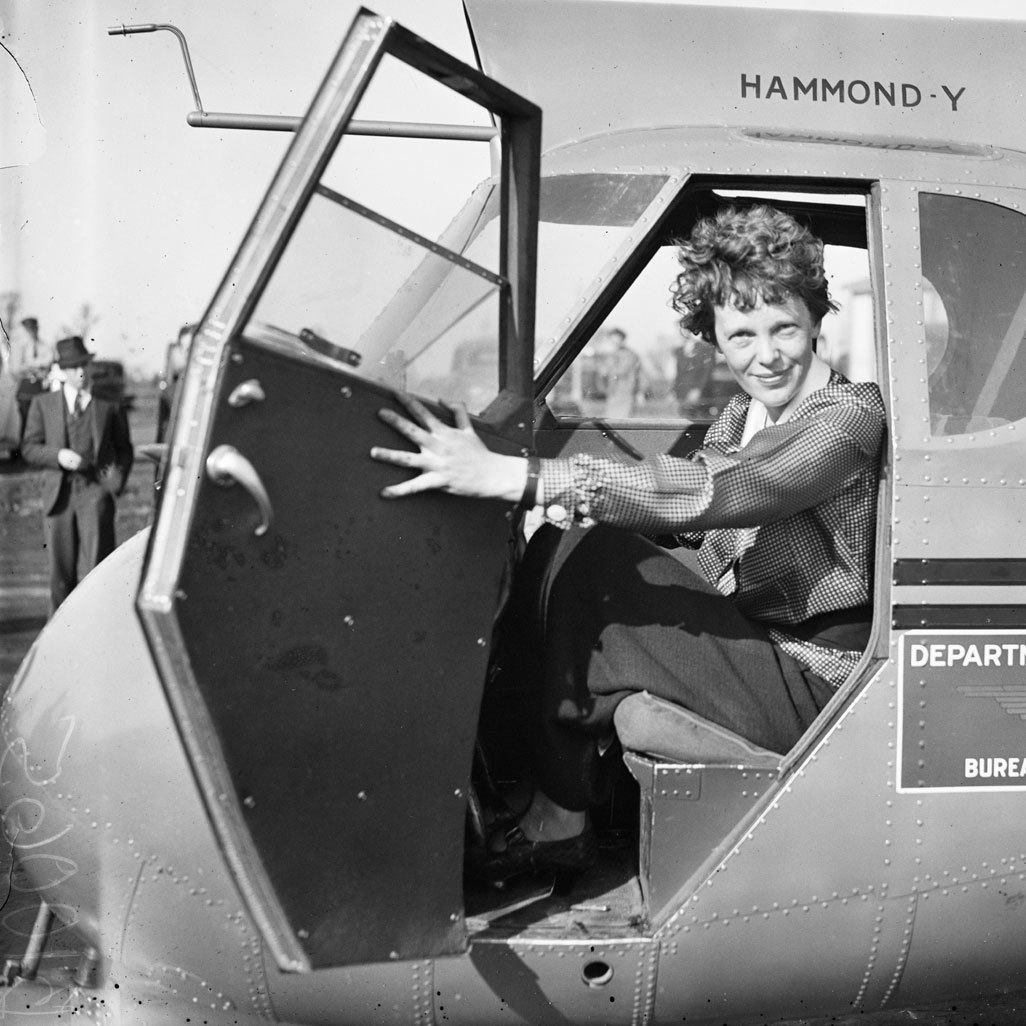 Amelia Earhart sitting inside a plane with it's door open