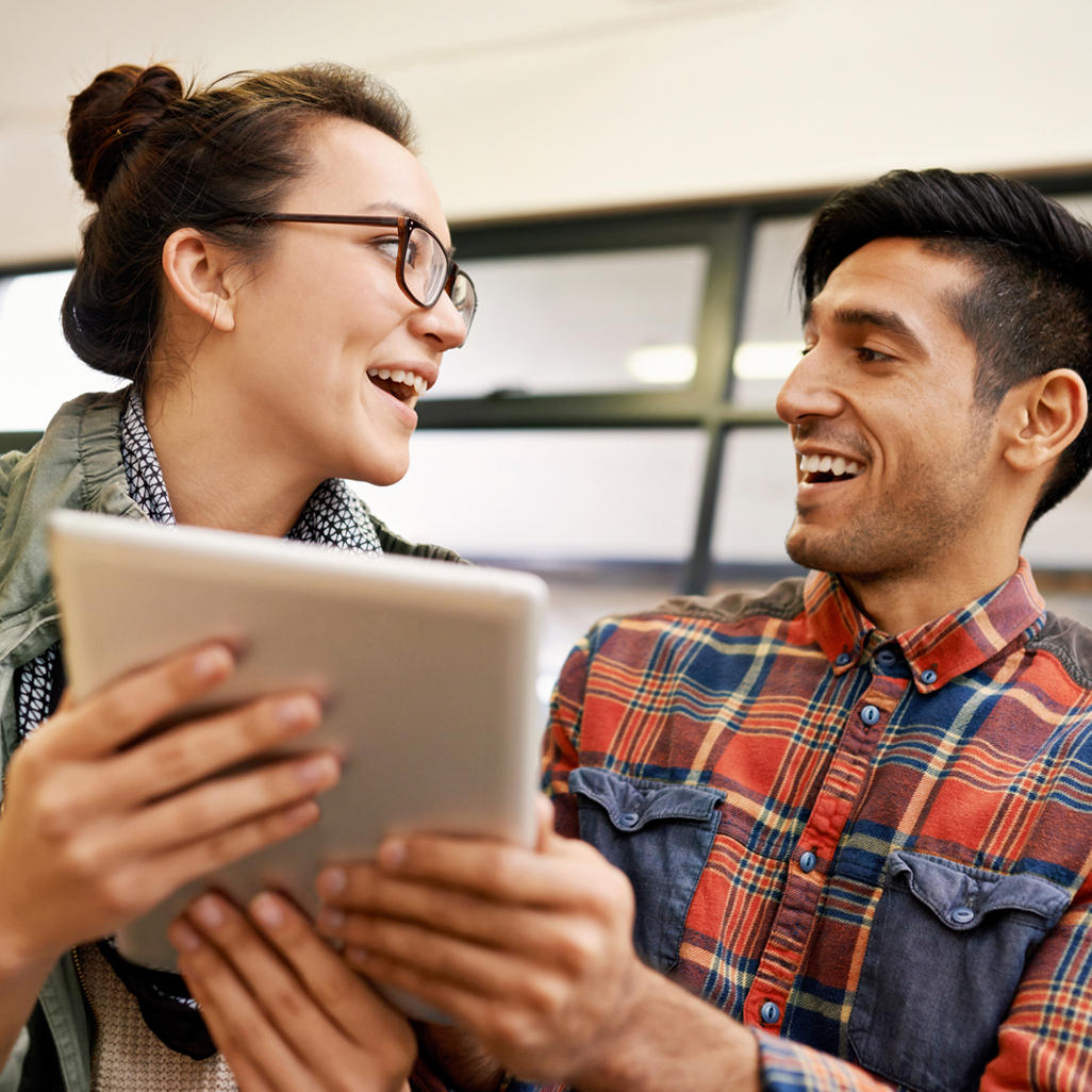 man and women looking at each other while holding tablet device