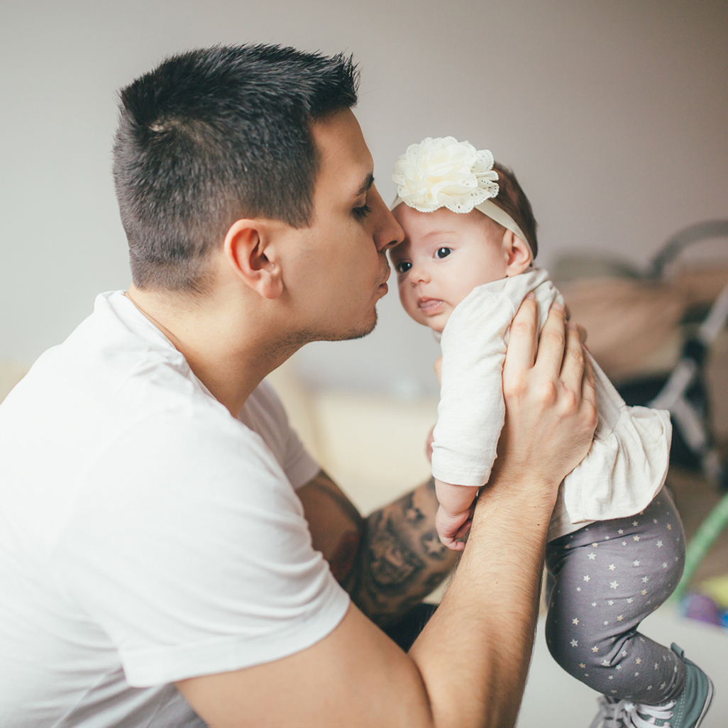 man holding a baby in his hands up high