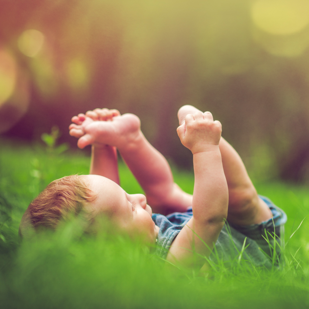 baby in grass holding feet