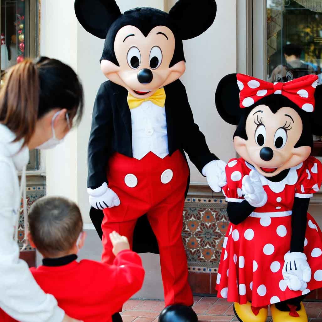 A parent and child greeting Mickey and Minnie Mouse