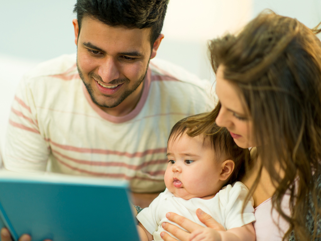 parents holding their baby on the lap and reading to her