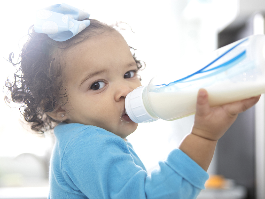 girl holding a baby bottle and drinking from it