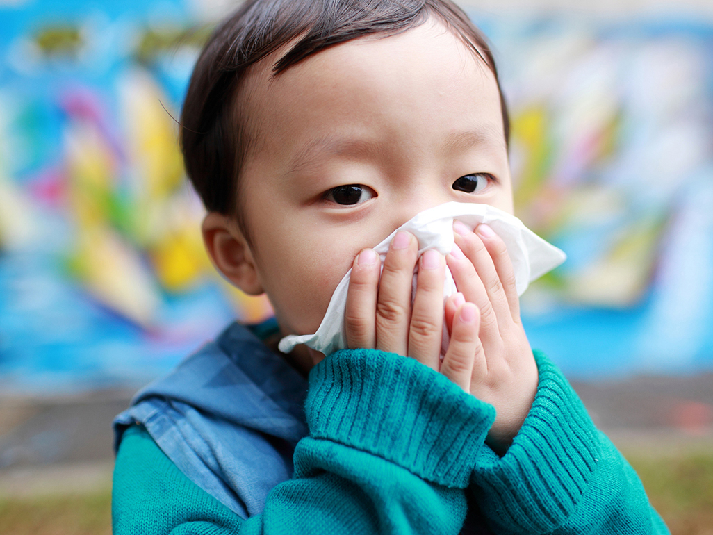 A toddler blowing their nose with a tissue