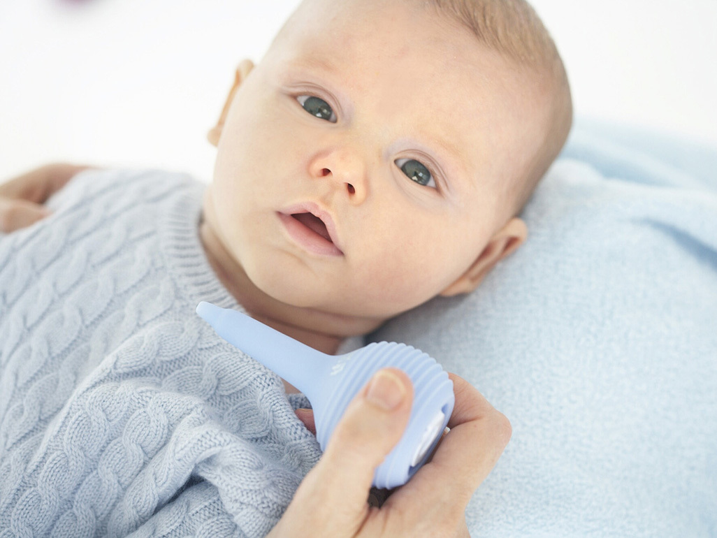 adult holding a nasal aspirator over a babys face