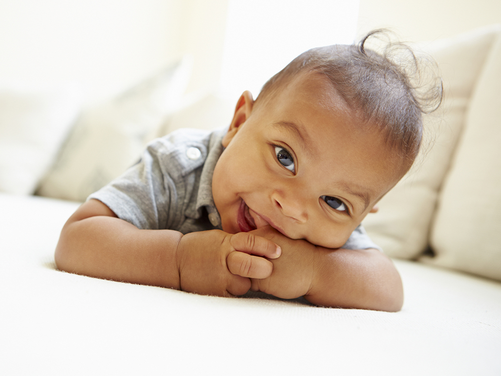 baby lying on his stomach with a finger in his mouth