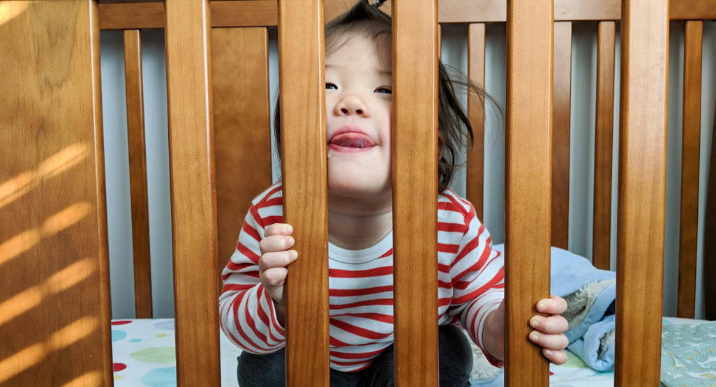 A toddler sitting up in a crib