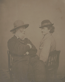 Walt Whitman and Peter Doyle face each other for a photographic portrait while wearing hats. 
