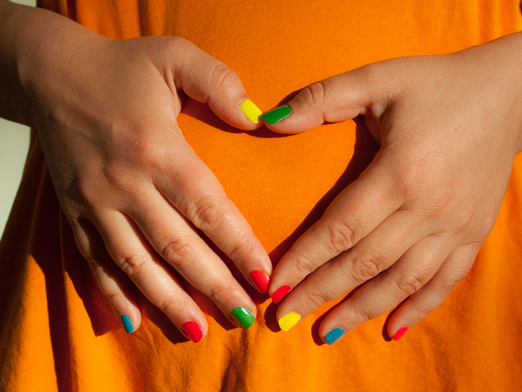 woman wearing colorful nail polish holding her pregnant belly