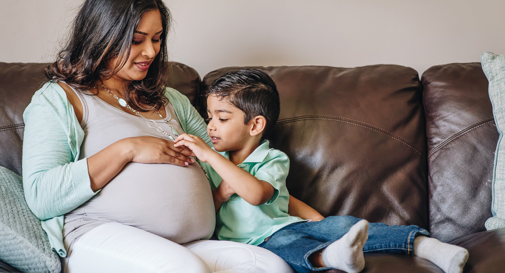 embarazada con niño que le acaricia la panza