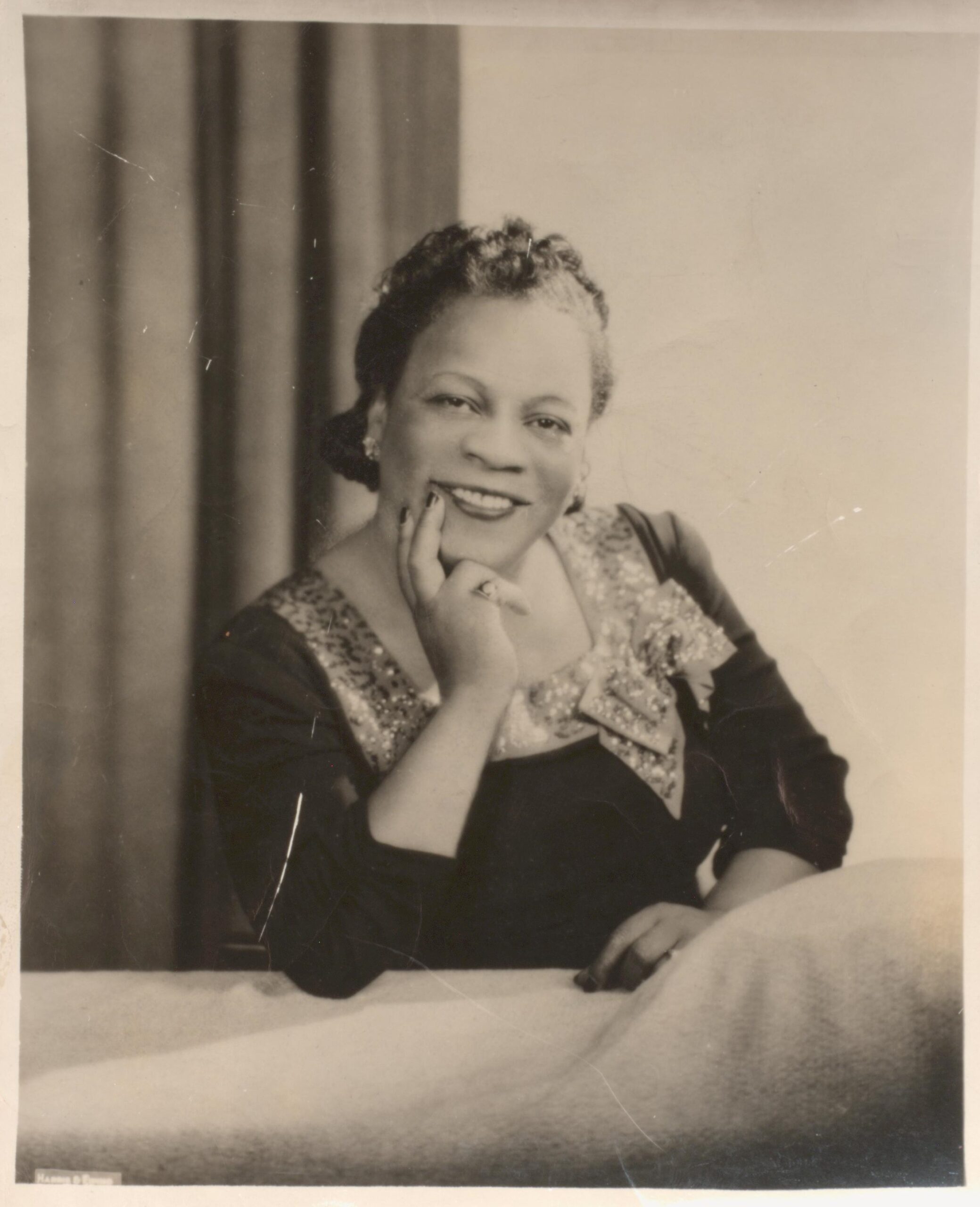 Black and white photograph portrait of Mary Cardwell Dawson seated at a table, elbow rested on table and hand posed under her chin.