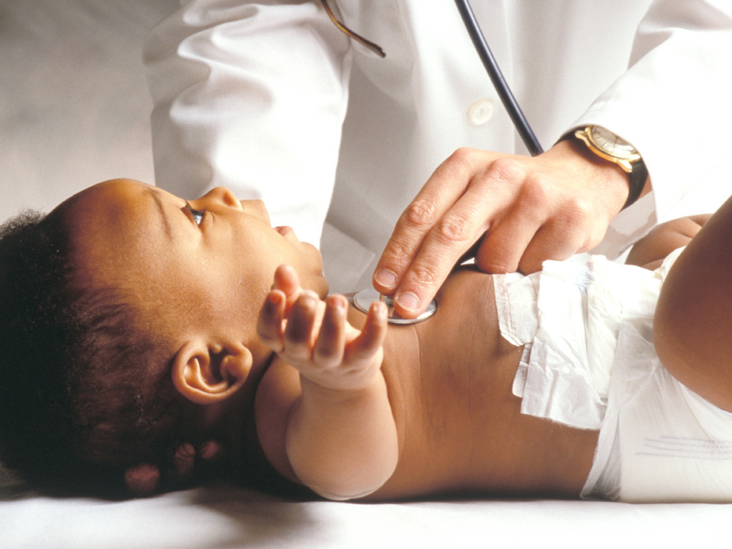 newborn lying on a hospital bed examined by a doctor