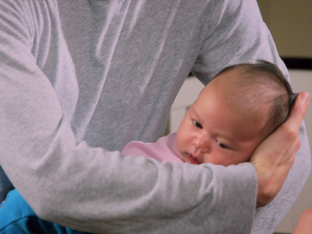 man awkwardly holding a baby and cradling her head