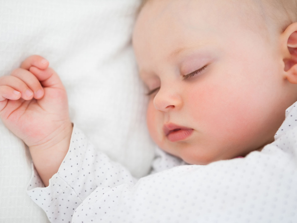 Baby in nappy sleeping in a cot