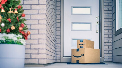 An image of two Amazon delivery boxes on the floor of a front door with a Christmas tree to the left.