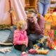 A family of four, including a toddler, a baby, and their parents, are playing together indoors with a toy.