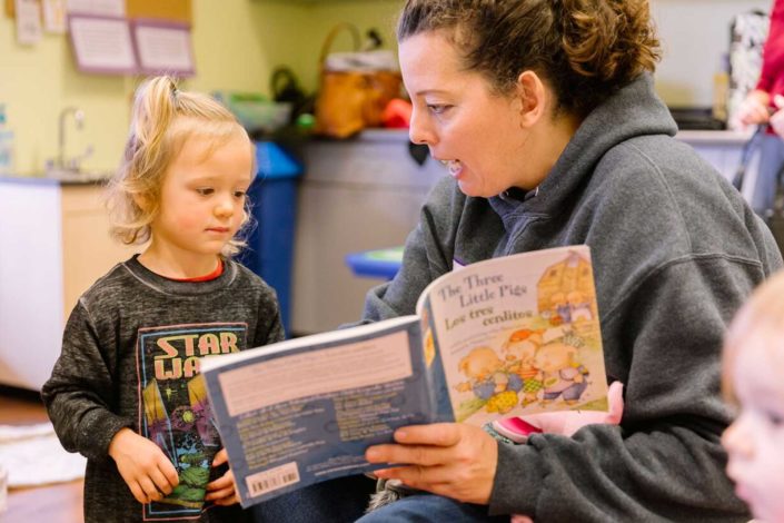 A person is reading a book with a child.