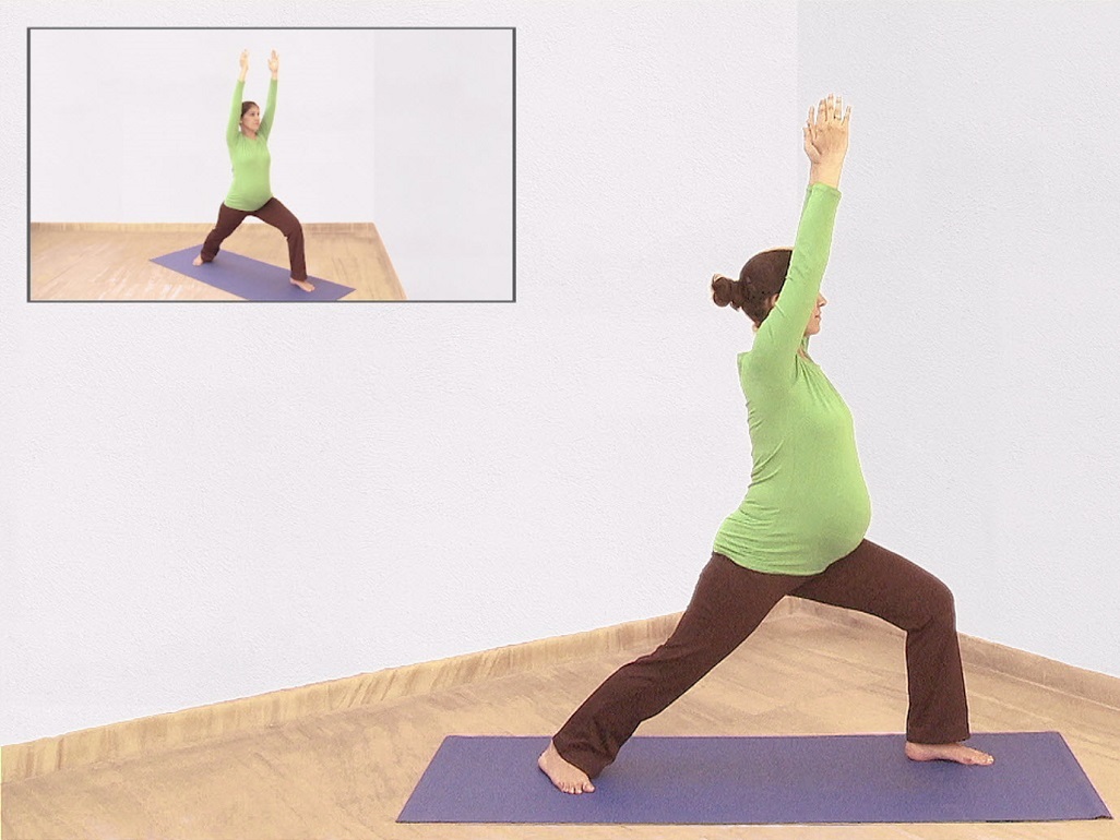 pregnant woman on yoga mat with hands overhead