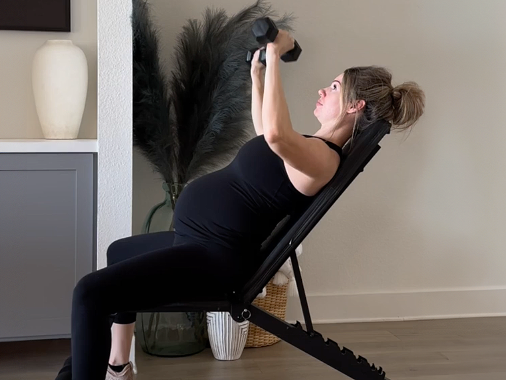 Anna Victoria demonstrating lifting weights sitting at an angle