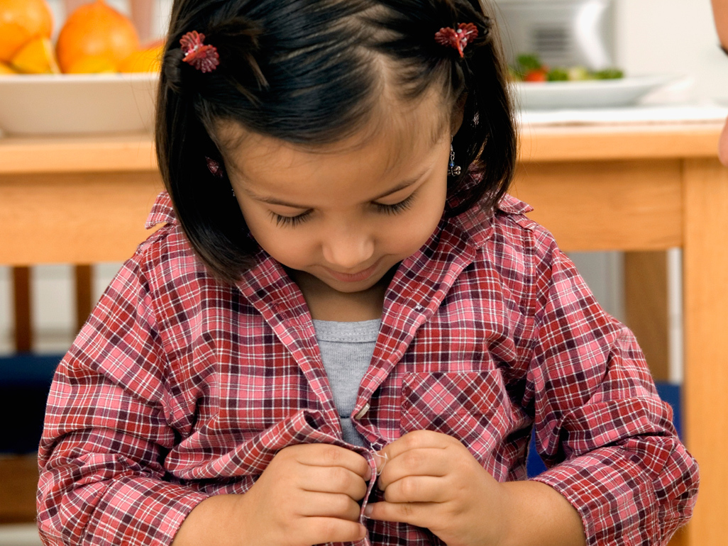 Toddler doing up shirt buttons