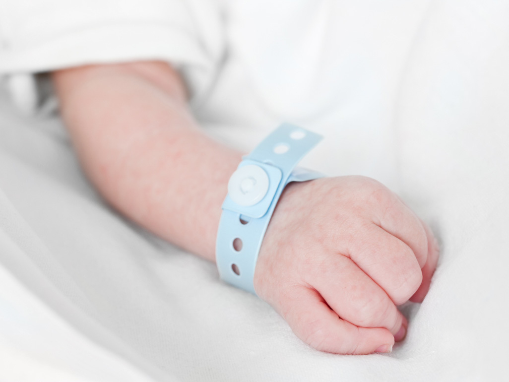 close up shot of a newborn's hand with name tag