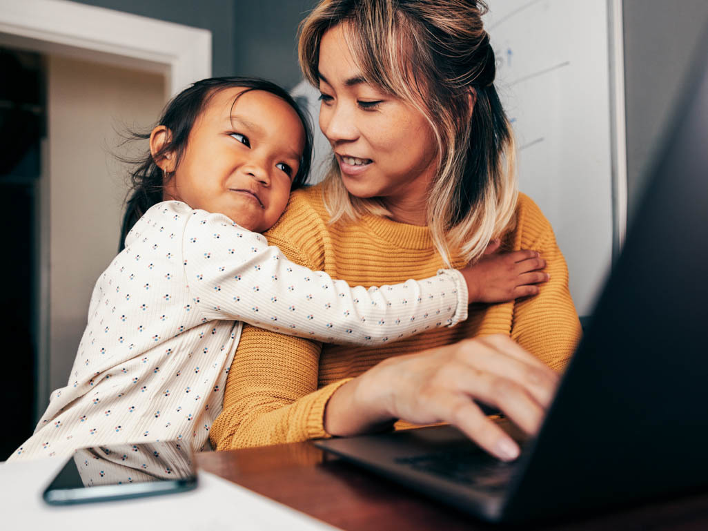 child hugging mom while she's working