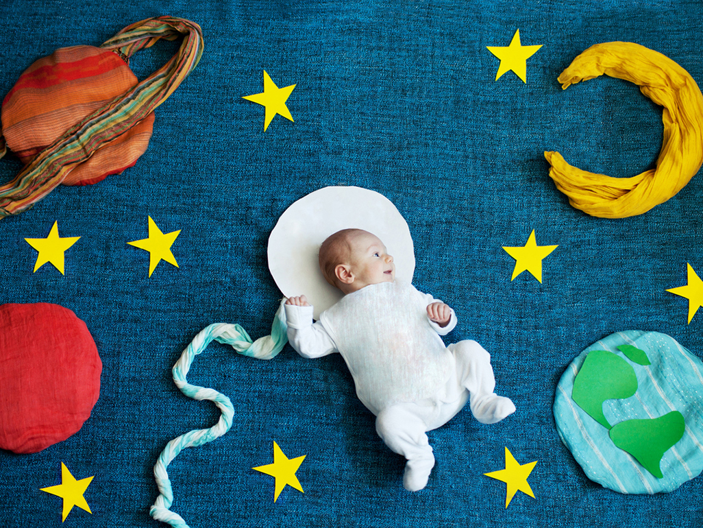 A baby lying on a blanket with space-themed props