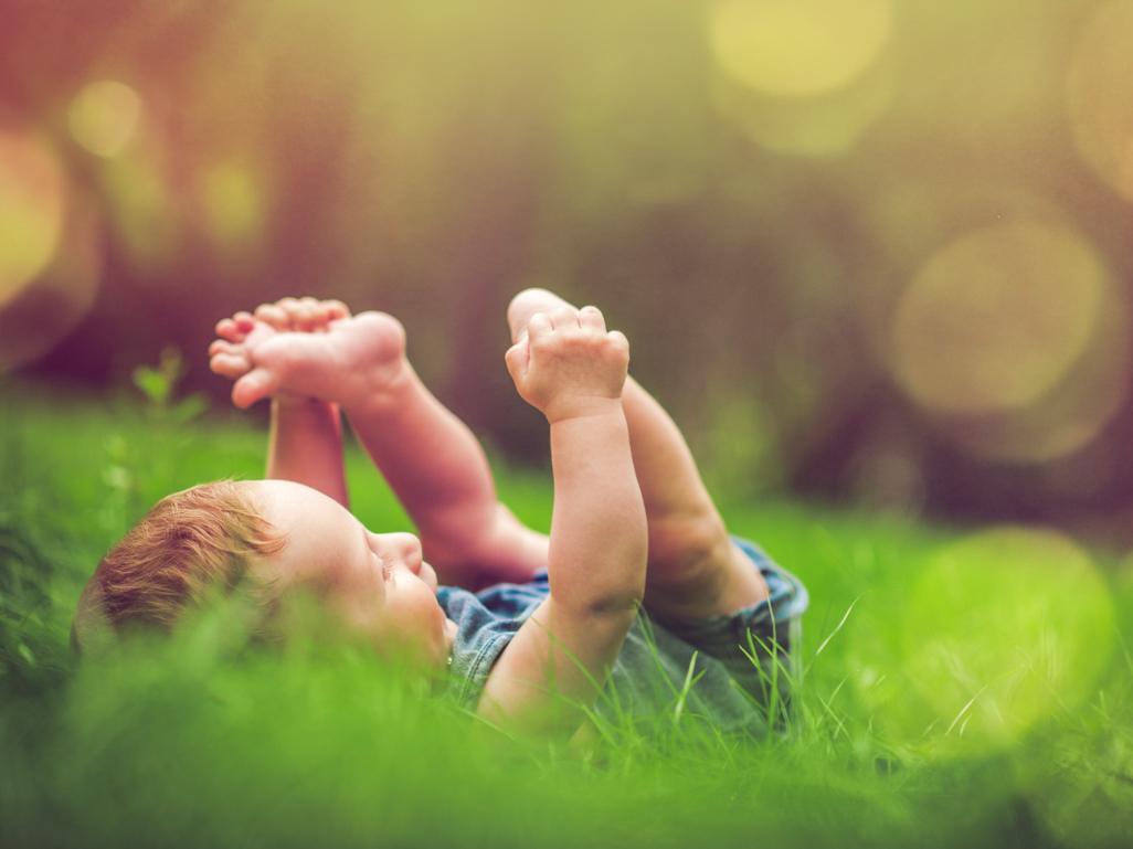 baby in grass holding feet