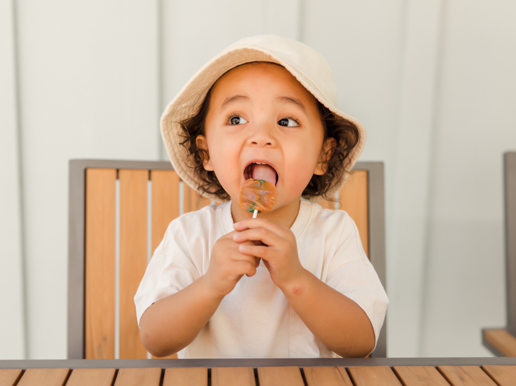 A toddler eating a lollipop outside