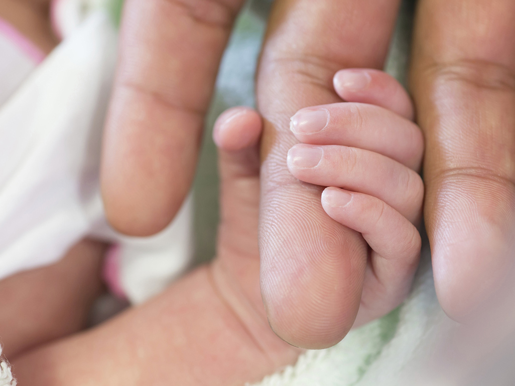 baby grasping Mom's finger