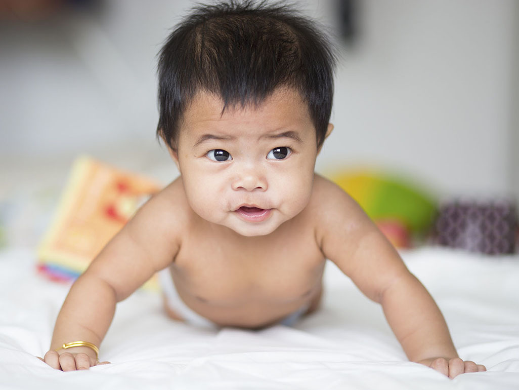 happy baby on tummy pushing up on their hands