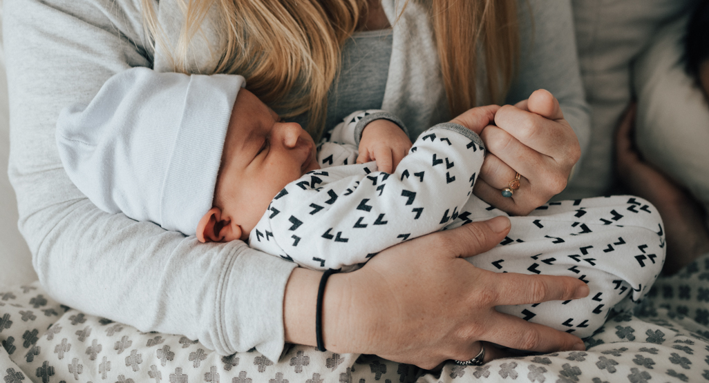 mother holding newborn baby in lap