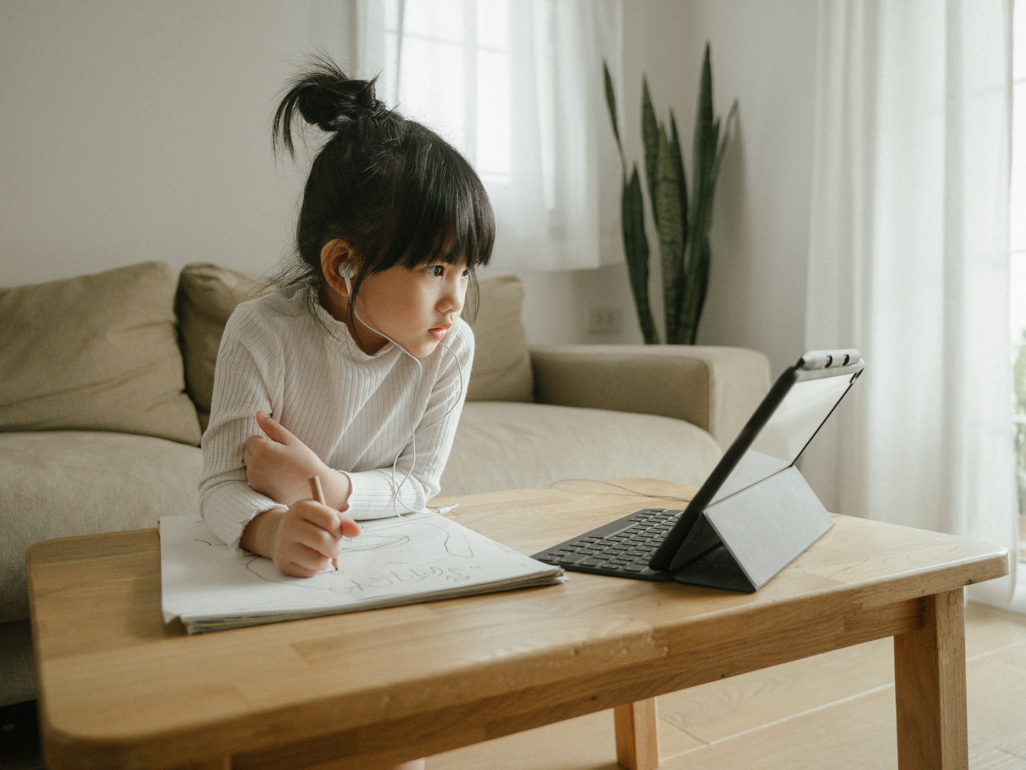 young girl studying while looking at tablet device