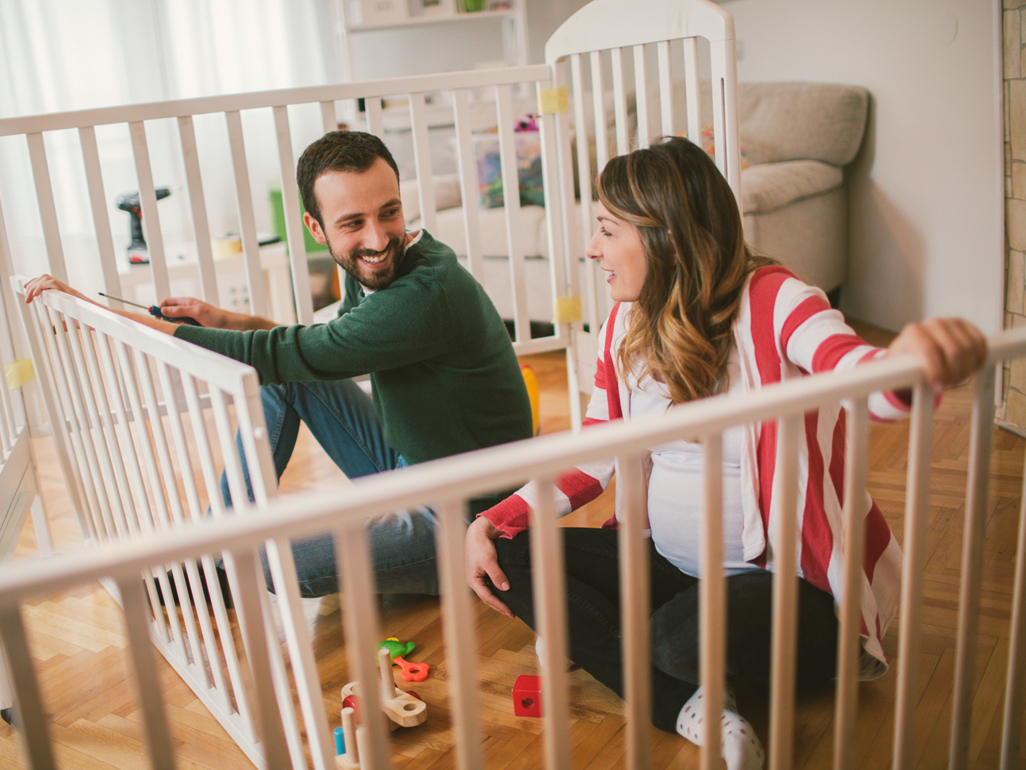 A man and a pregnant woman putting together a crib