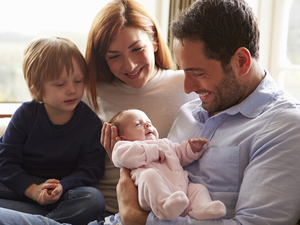 father holding a baby while mother and a son are watching