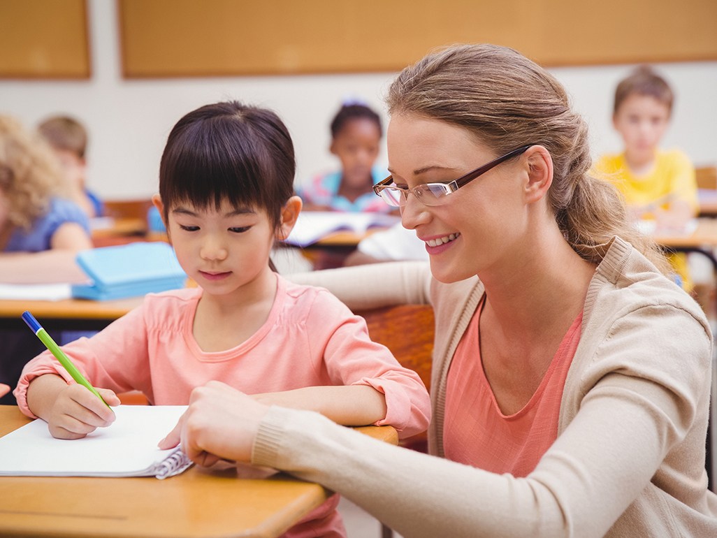 teacher explaining something to the girl in the classroom