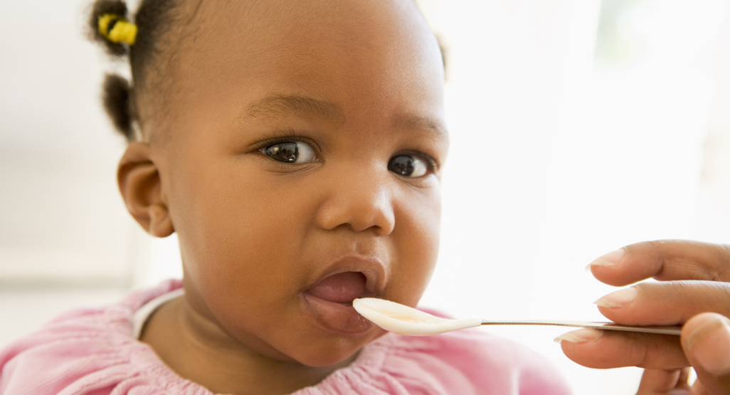 girl being fed from a plastic spoon