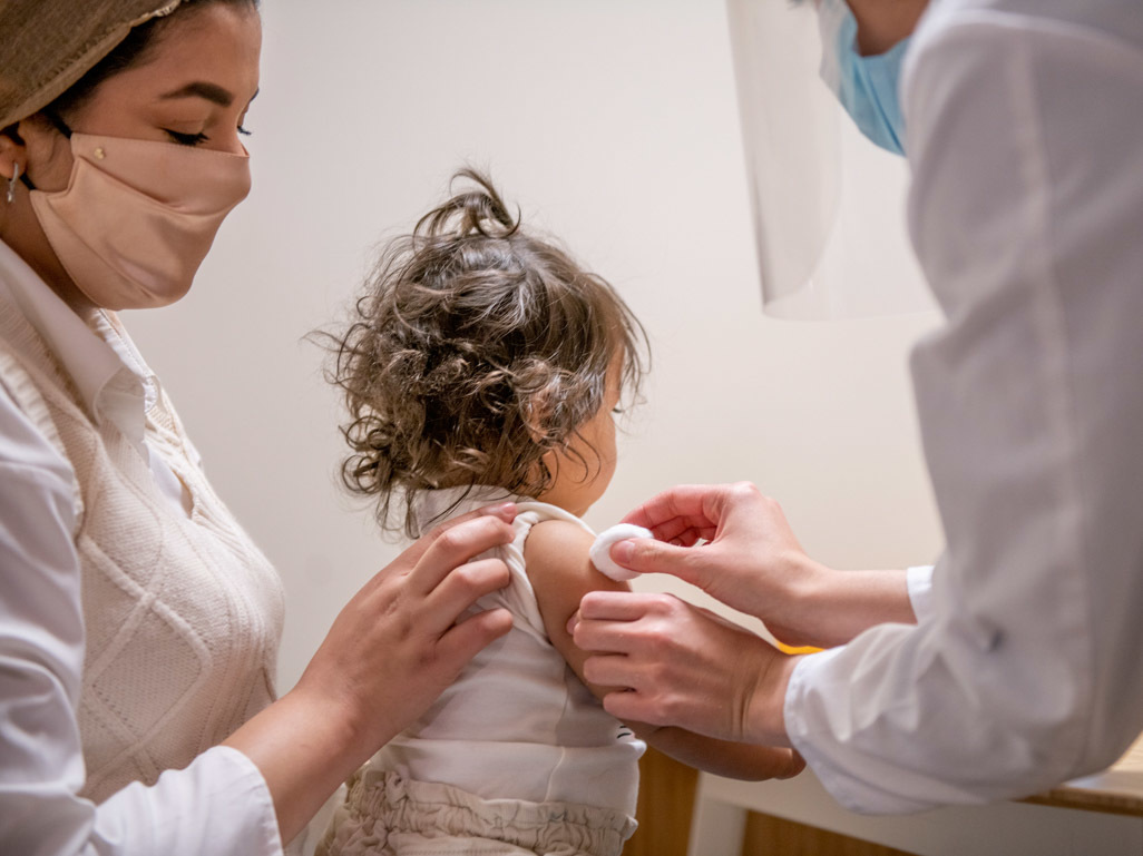 Toddler getting vaccine with lollipop