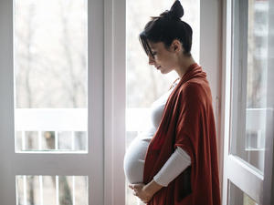 side view of a pregnant woman looking down at her pregnant stomach