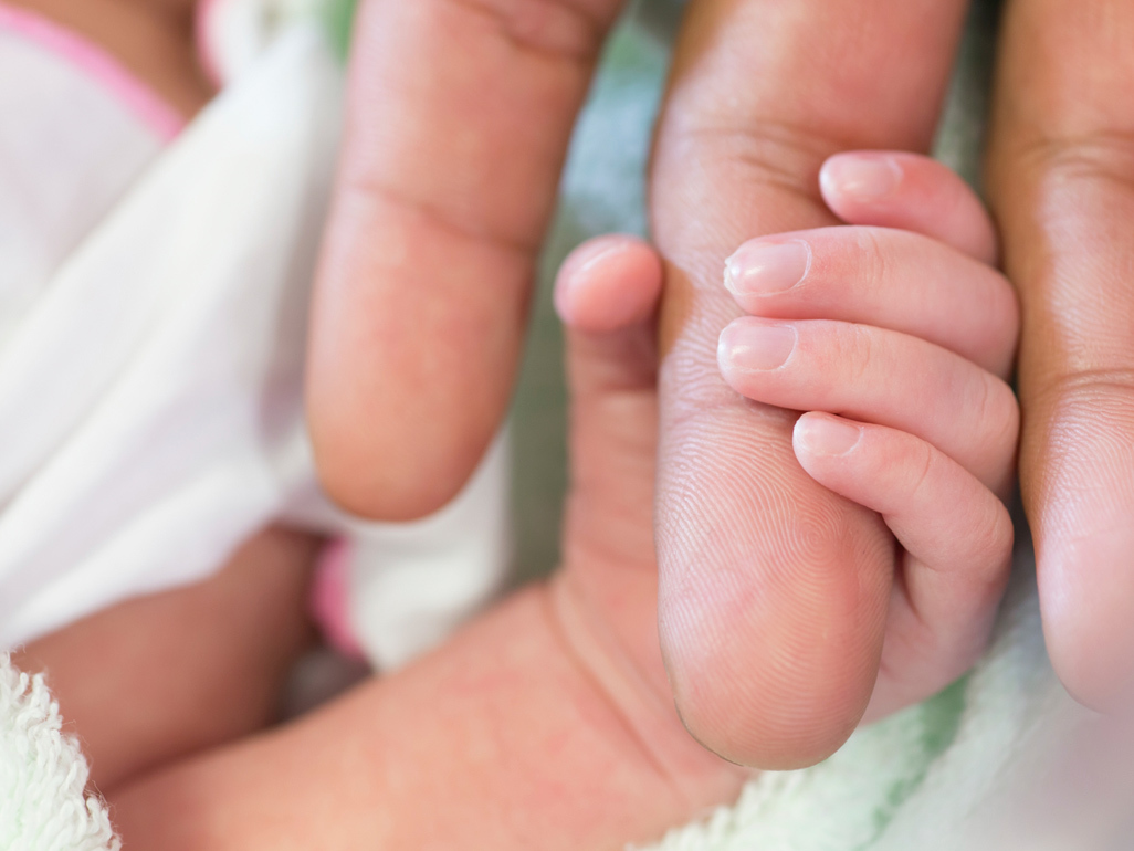 baby's hand holding onto adult's finger