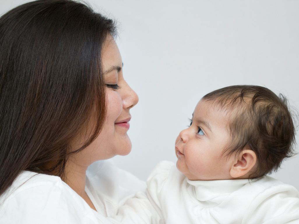 Mum holding and smiling at baby