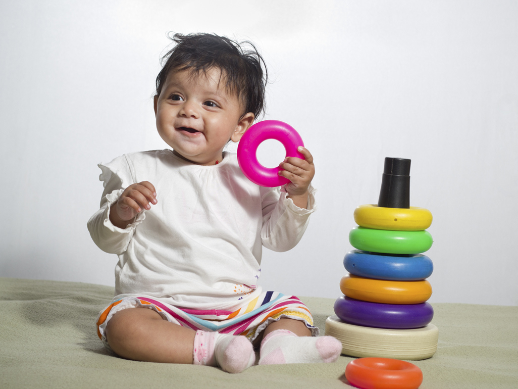 smiling baby girl sitting up stacking rings